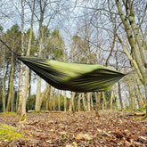 DD Recycled Camping Hammock hanging between trees, made from recycled plastic bottles for eco-friendly outdoor adventures.